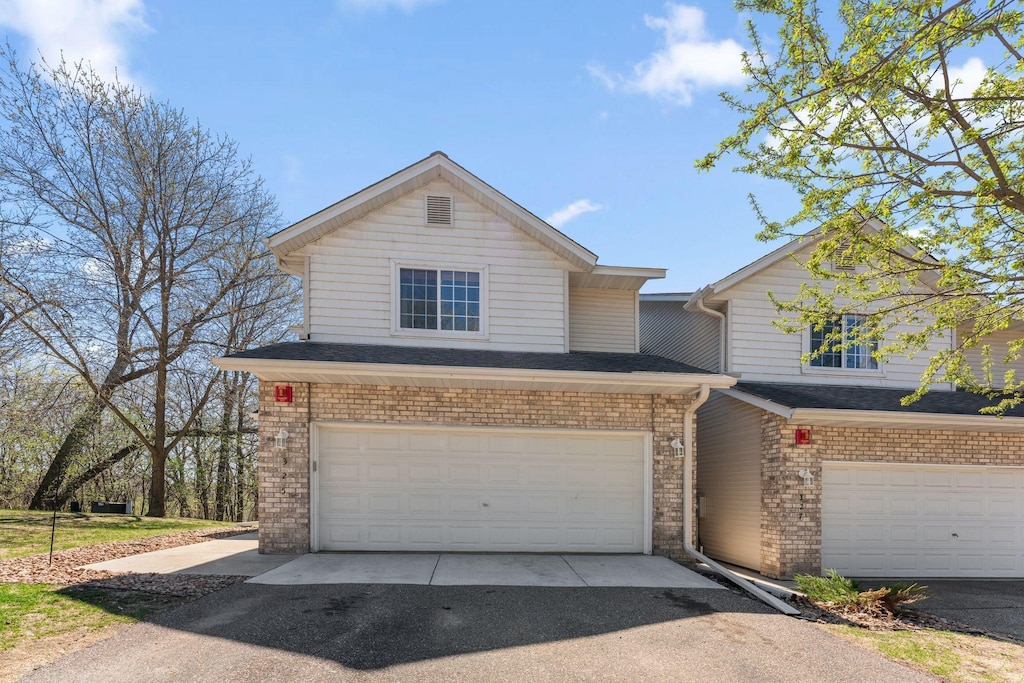 view of front facade with an attached garage, aphalt driveway, and brick siding