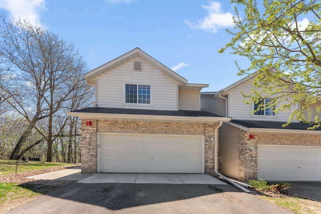 view of front facade with an attached garage, aphalt driveway, and brick siding
