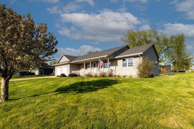 single story home with an attached garage, a front lawn, covered porch, and concrete driveway