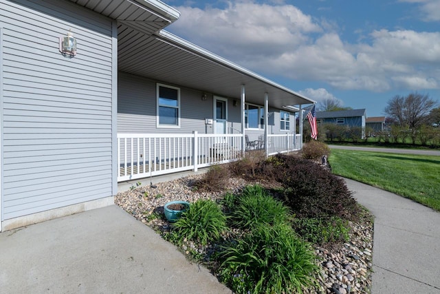 view of exterior entry featuring covered porch and a yard