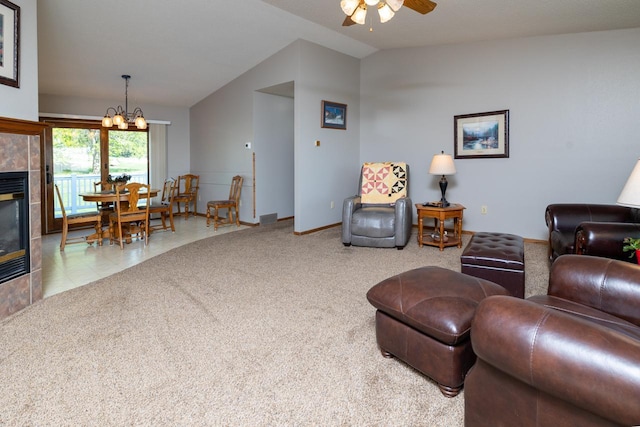 carpeted living room featuring lofted ceiling, ceiling fan, a chandelier, and a tile fireplace