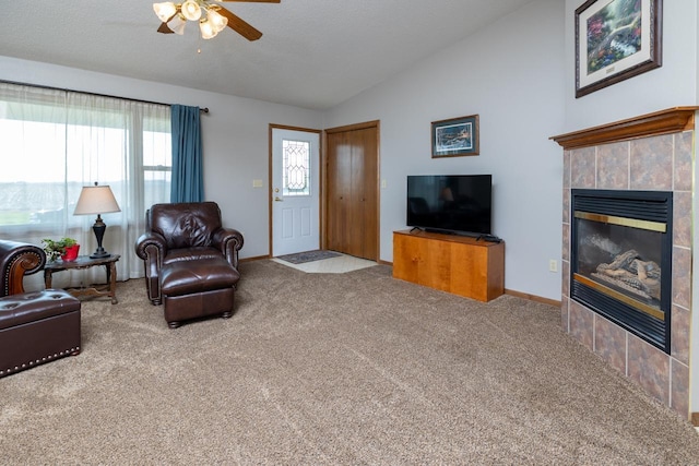 living area with vaulted ceiling, ceiling fan, carpet flooring, a fireplace, and baseboards