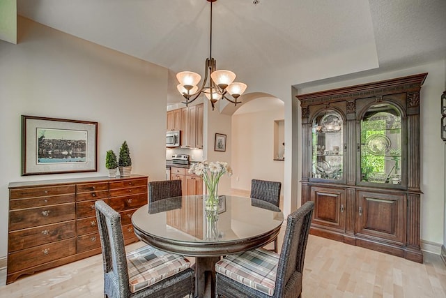650 Main St N Unit 308, Stillwater, MN 55082 - dining space with arched walkways, a chandelier, light wood-style flooring, and baseboards