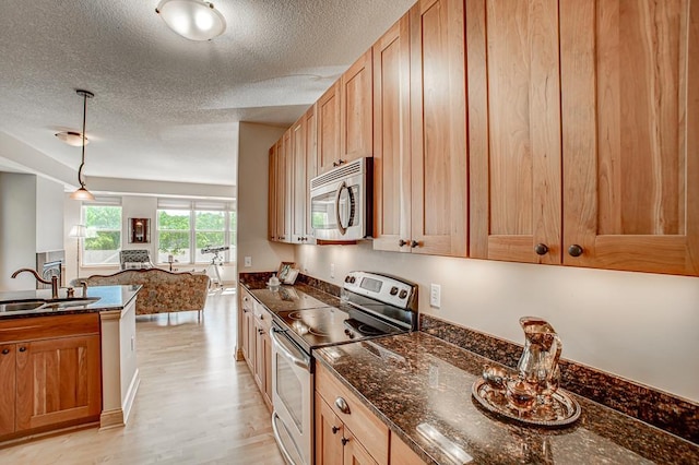 650 Main St N Unit 308, Stillwater, MN 55082 - kitchen featuring stainless steel appliances, a sink, a textured ceiling, open floor plan, and light wood-type flooring