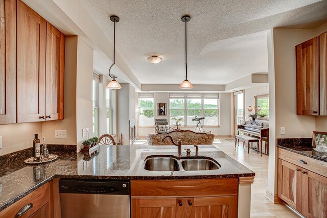 650 Main St N Unit 308, Stillwater, MN 55082 - kitchen featuring dishwasher, a sink, dark stone counters, brown cabinetry, and a textured ceiling