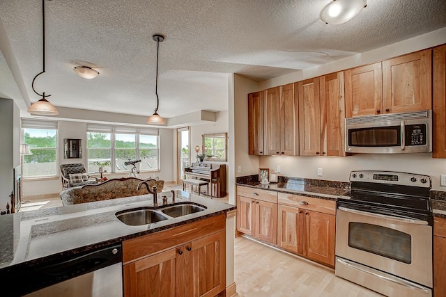 650 Main St N Unit 308, Stillwater, MN 55082 - kitchen featuring appliances with stainless steel finishes, a sink, dark stone counters, pendant lighting, and a textured ceiling