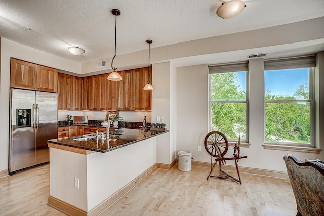 650 Main St N Unit 308, Stillwater, MN 55082 - kitchen with stainless steel refrigerator with ice dispenser, brown cabinets, light wood-style flooring, a sink, and a textured ceiling