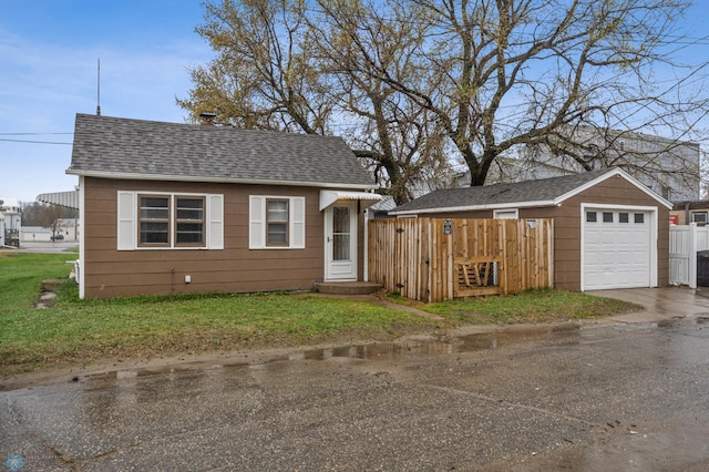 bungalow-style house featuring concrete driveway, a shingled roof, a front yard, and a garage