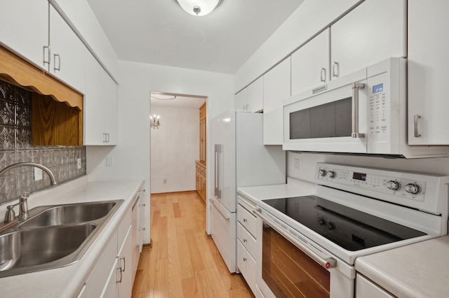 kitchen featuring white appliances, light countertops, white cabinets, a sink, and light wood finished floors