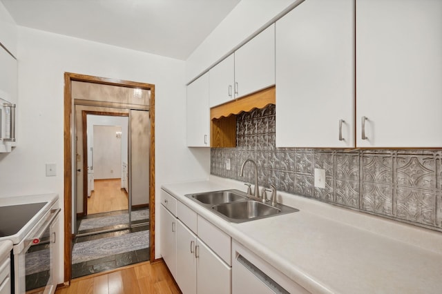 kitchen featuring a sink, light countertops, white range with electric cooktop, light wood-style flooring, and white cabinetry