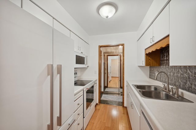 kitchen featuring a sink, white appliances, light countertops, white cabinetry, and light wood-type flooring