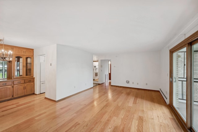 unfurnished living room featuring baseboards, an inviting chandelier, baseboard heating, and light wood-style flooring