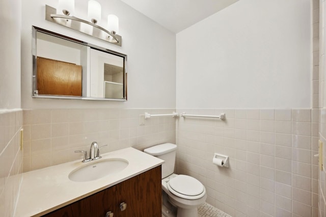 bathroom with wainscoting, tile walls, vanity, and toilet