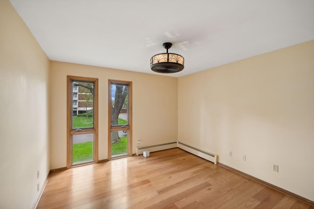 empty room with baseboards, a baseboard heating unit, and light wood-type flooring