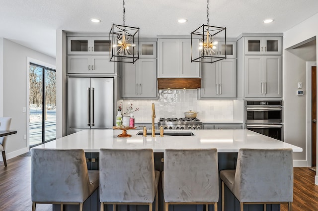 2451 180th Ln NE, Ham Lake, MN 55304 - kitchen featuring an inviting chandelier, appliances with stainless steel finishes, a kitchen island with sink, and a sink
