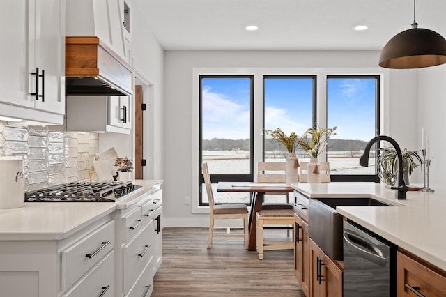 kitchen with backsplash, pendant lighting, appliances with stainless steel finishes, light wood-type flooring, and light countertops