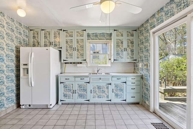 kitchen featuring wallpapered walls, a wealth of natural light, a sink, and white fridge with ice dispenser