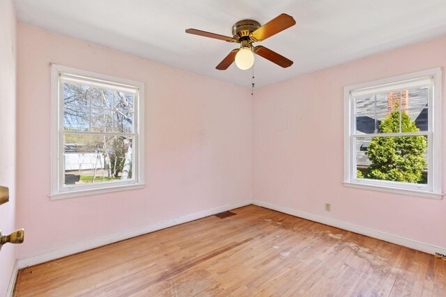 empty room featuring light wood-type flooring, a ceiling fan, baseboards, and visible vents
