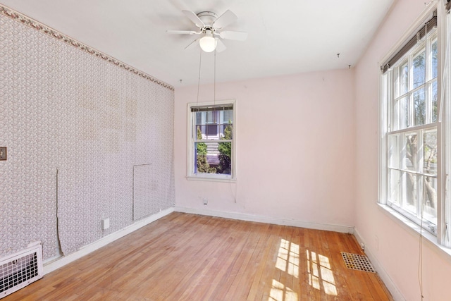 unfurnished room with light wood-type flooring, baseboards, ceiling fan, and visible vents