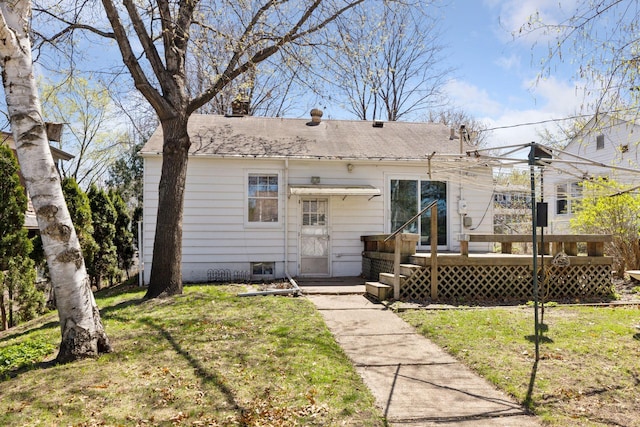 rear view of house featuring a chimney, a yard, and a deck