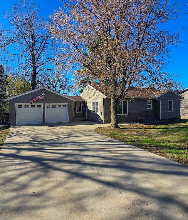 ranch-style house with driveway, stone siding, and a garage