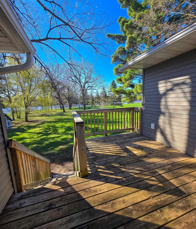 wooden terrace featuring a lawn and a water view