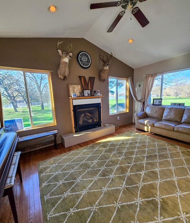 living room featuring a glass covered fireplace, wood finished floors, recessed lighting, a ceiling fan, and vaulted ceiling