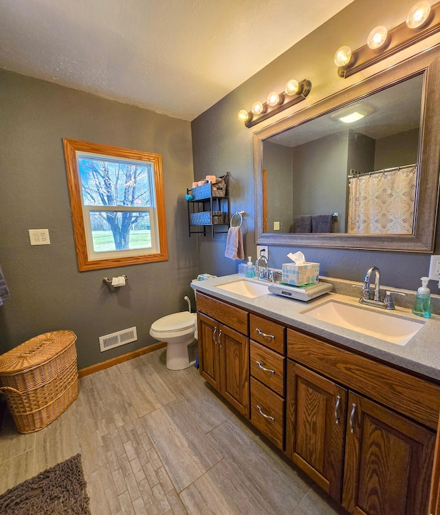 full bath featuring visible vents, a sink, wood finished floors, and double vanity