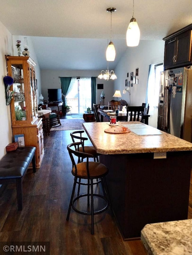 kitchen featuring a kitchen breakfast bar, a kitchen island, dark wood finished floors, light countertops, and lofted ceiling