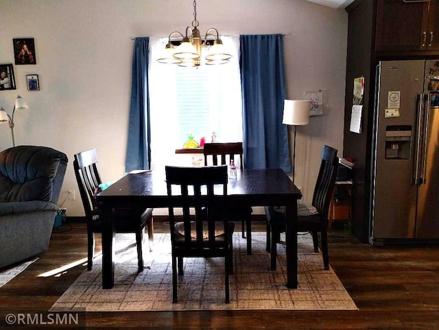 dining area with an inviting chandelier, wood finished floors, and vaulted ceiling