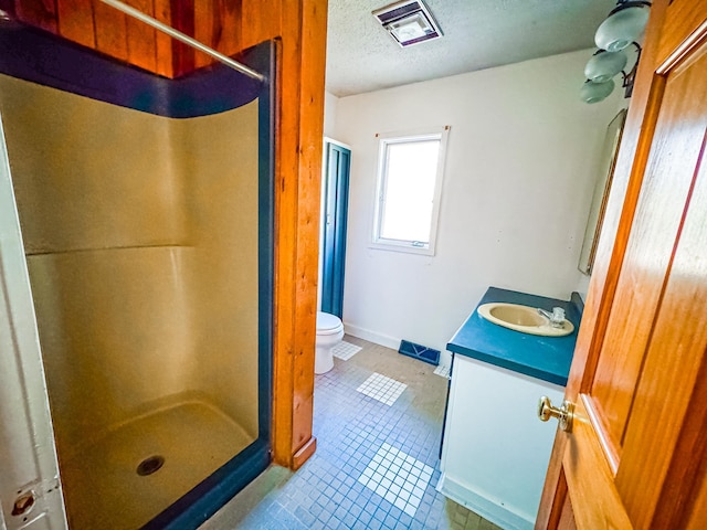 bathroom with toilet, tile patterned floors, a textured ceiling, and a stall shower