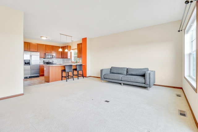 living room featuring baseboards, light carpet, and visible vents