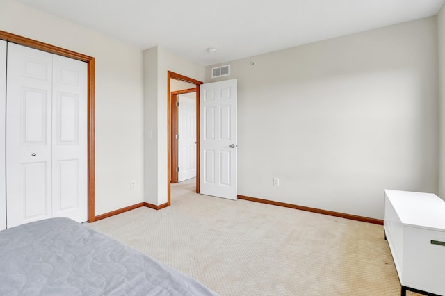 unfurnished bedroom featuring baseboards, visible vents, light carpet, and a closet