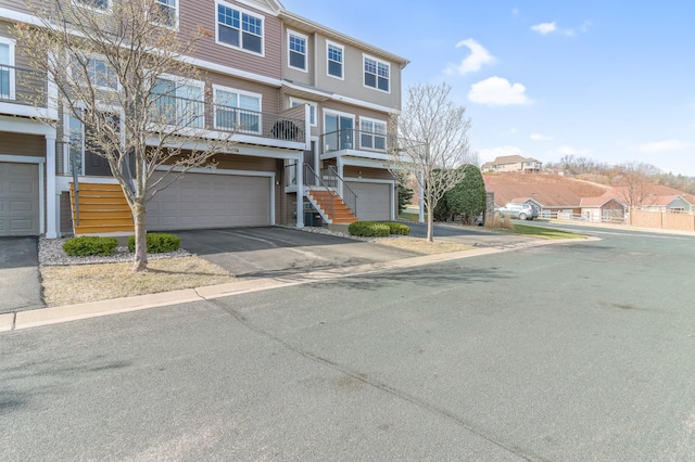 multi unit property with stairs, an attached garage, and aphalt driveway