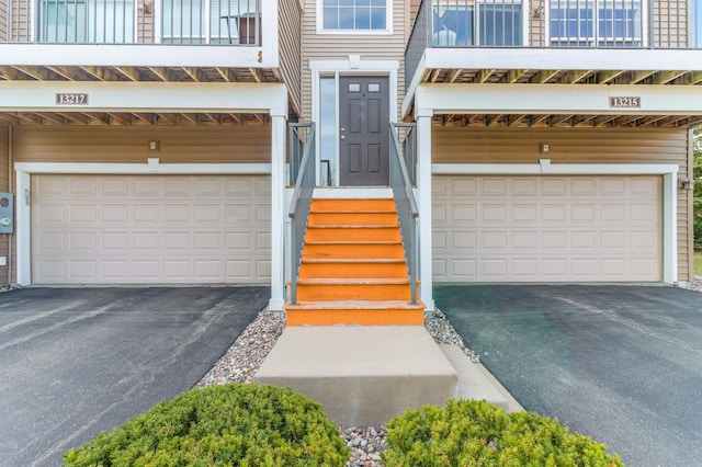 property entrance featuring an attached garage and aphalt driveway