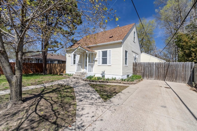 bungalow featuring fence and roof with shingles