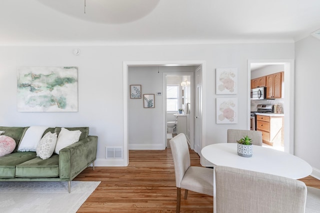 dining area featuring baseboards, light wood-style flooring, and visible vents