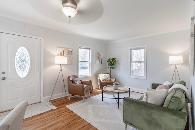 living room with light wood-style floors, baseboards, and a ceiling fan