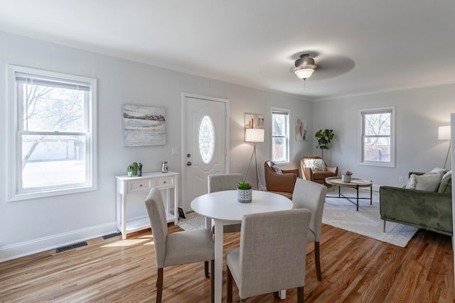 dining room featuring ceiling fan, visible vents, baseboards, and light wood-style floors