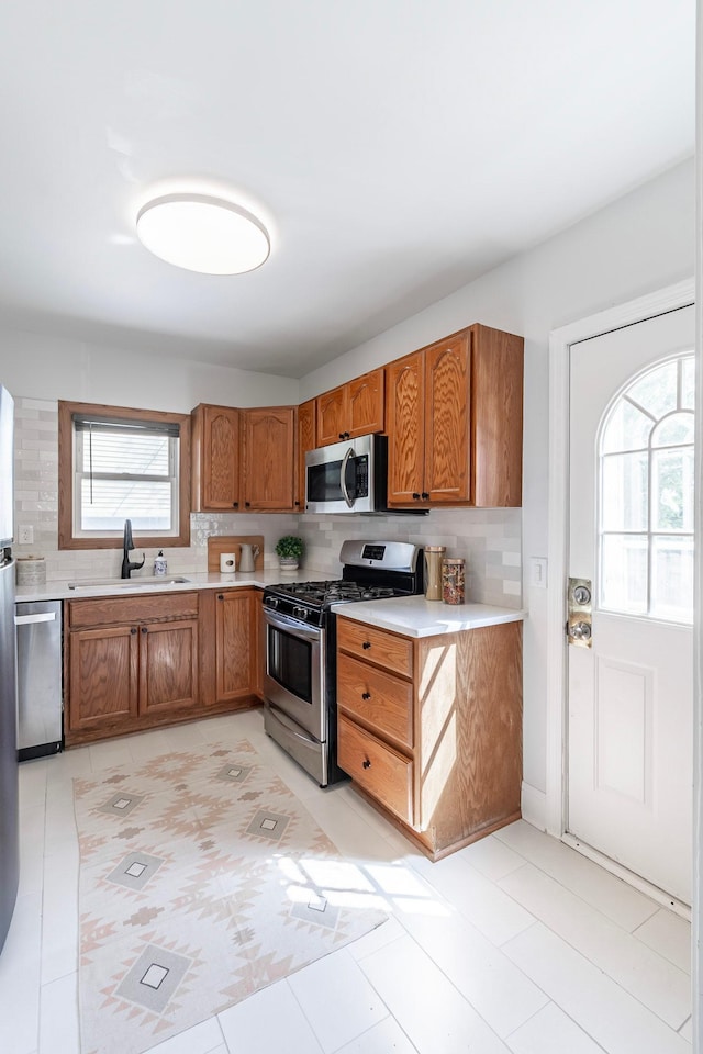 kitchen with a sink, appliances with stainless steel finishes, backsplash, and brown cabinets