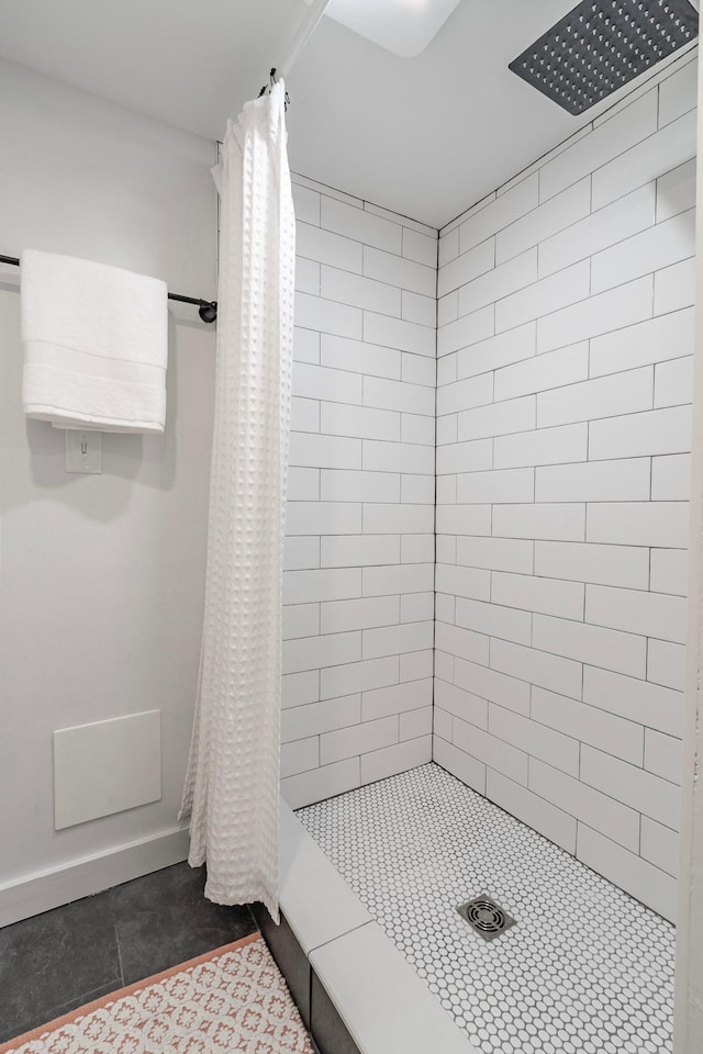 full bath featuring baseboards, tile patterned floors, and tiled shower