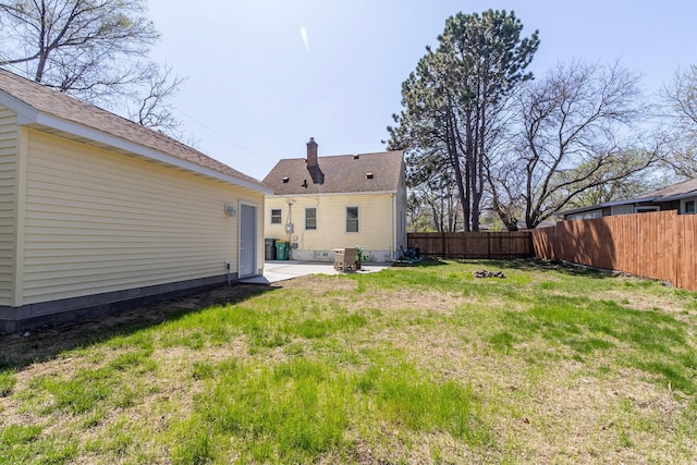 rear view of property with a lawn, a fenced backyard, a patio area, and a chimney