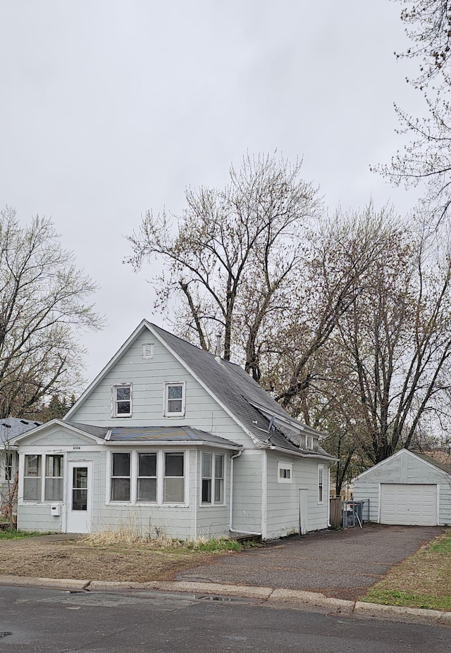 view of front of home featuring a detached garage, an outdoor structure, a shingled roof, and aphalt driveway