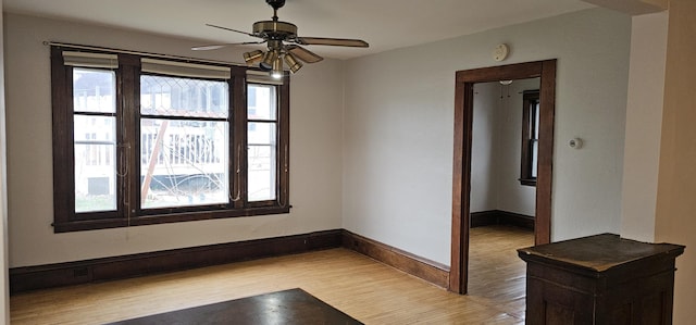 empty room with a ceiling fan, baseboards, and light wood-style floors