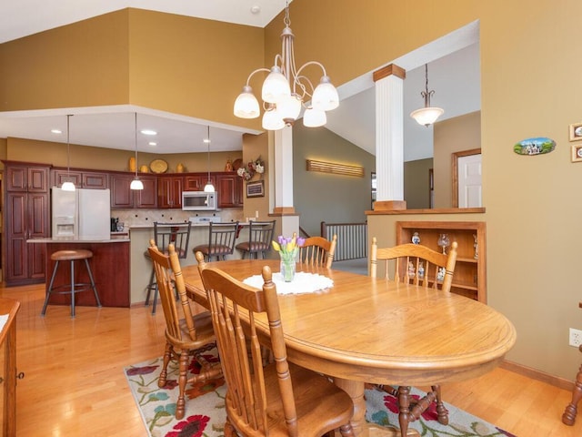 dining space with high vaulted ceiling, an inviting chandelier, and light wood-type flooring