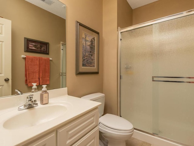 bathroom with vanity, tile patterned floors, a stall shower, and toilet