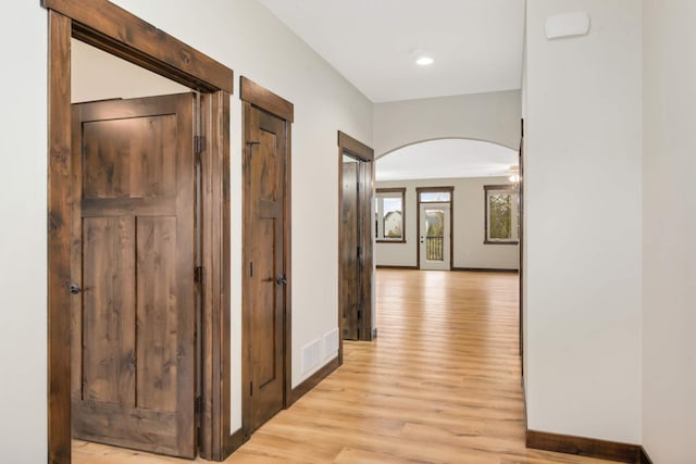 12891 Xylite St NE, Blaine, MN 55449 - hallway with light wood-type flooring, arched walkways, baseboards, and visible vents