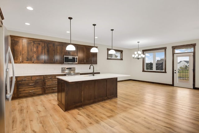 12891 Xylite St NE, Blaine, MN 55449 - kitchen with light wood-style floors, light countertops, a chandelier, stainless steel appliances, and decorative backsplash