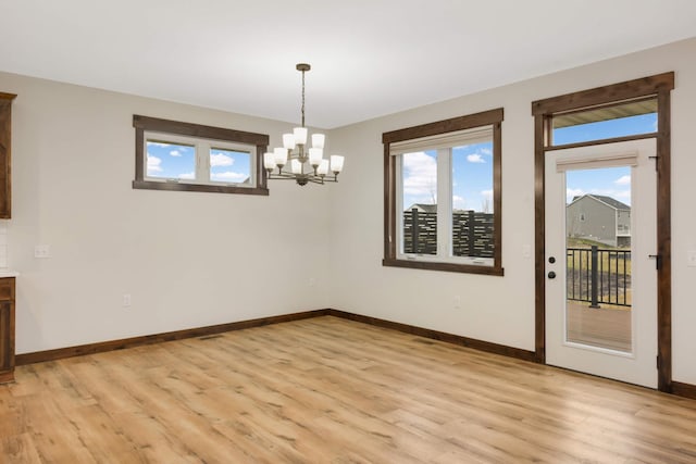 12891 Xylite St NE, Blaine, MN 55449 - unfurnished dining area with baseboards, light wood-type flooring, and a chandelier