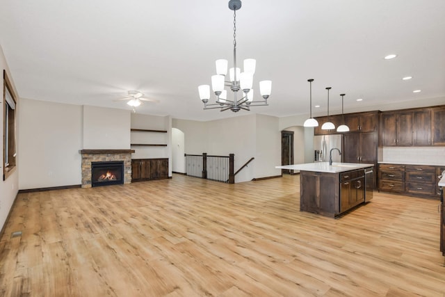 12891 Xylite St NE, Blaine, MN 55449 - kitchen featuring dark brown cabinetry, arched walkways, appliances with stainless steel finishes, ceiling fan with notable chandelier, and light wood-style flooring